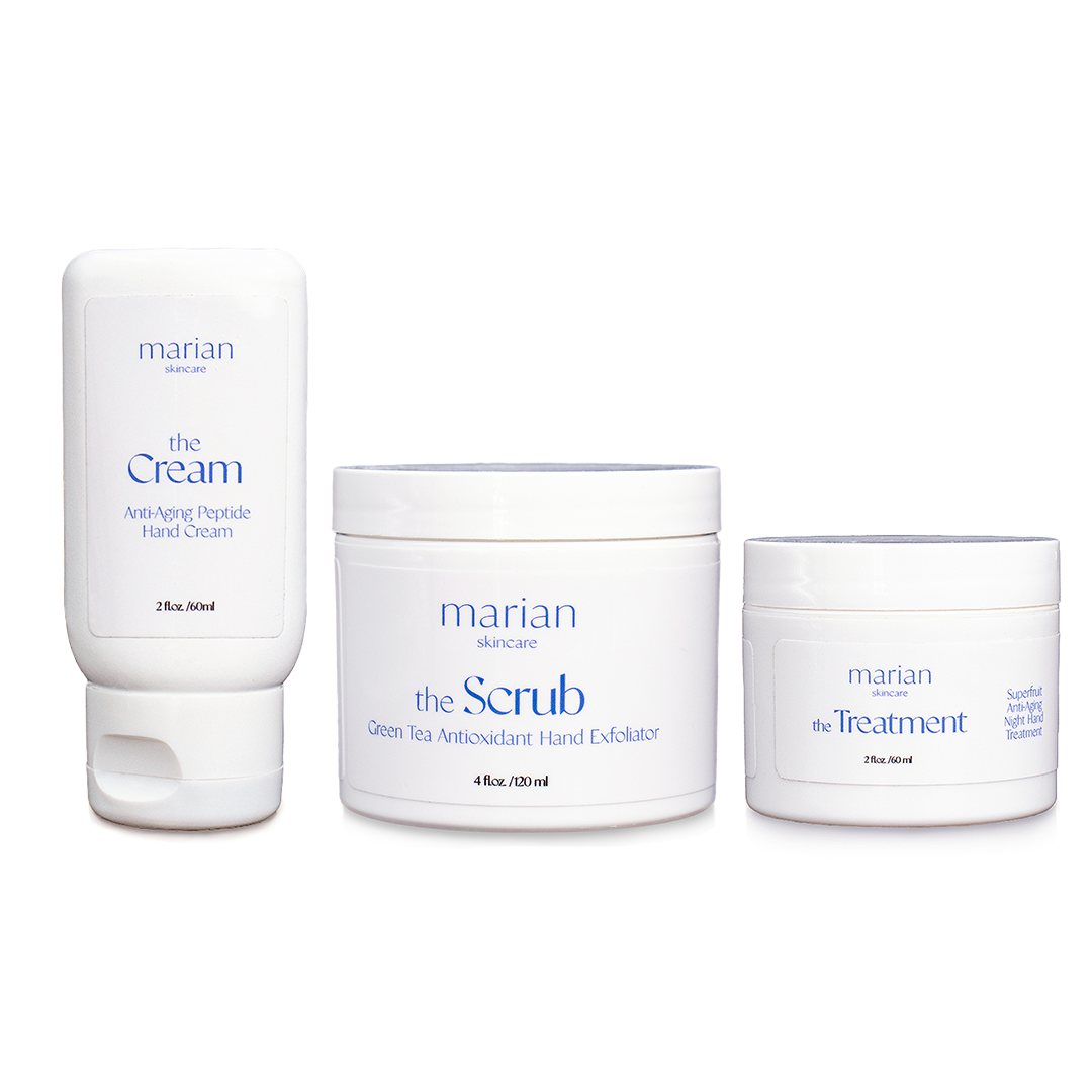 marian skincare the Set - three products in white containers with periwinkle lettering on a white background. Left is a squeezable bottle labeled "marian skincare, the Cream, Anti-Aging, Peptide Hand Cream, 2 fluid ounces, 60 milliliters". Center is a round jar labeled "marian skincare the Scrub Green Tea Antioxidant Hand Exfoliator, 4 fluid ounces, 120 milliliters". Right is a round jar labeled "marian skincare the Treatment Superfruit Anti-Aging Night Hand Treatment, 2 fluid ounces, 60 milliliters"