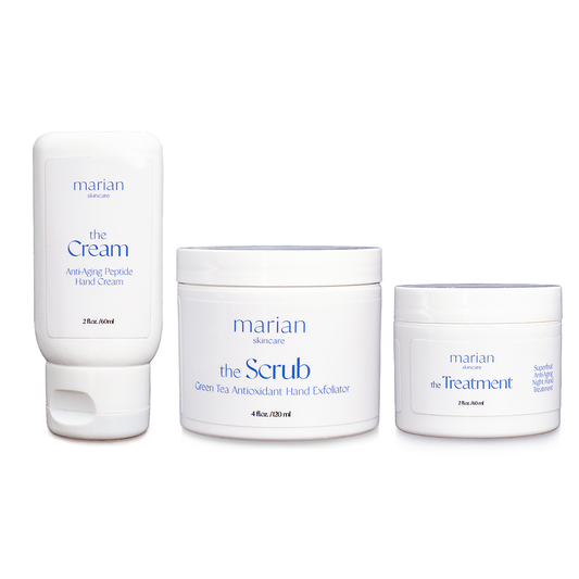 marian skincare the Set - three products in white containers with periwinkle lettering on a white background. Left is a squeezable bottle labeled "marian skincare, the Cream, Anti-Aging, Peptide Hand Cream, 2 fluid ounces, 60 milliliters". Center is a round jar labeled "marian skincare the Scrub Green Tea Antioxidant Hand Exfoliator, 4 fluid ounces, 120 milliliters". Right is a round jar labeled "marian skincare the Treatment Superfruit Anti-Aging Night Hand Treatment, 2 fluid ounces, 60 milliliters"