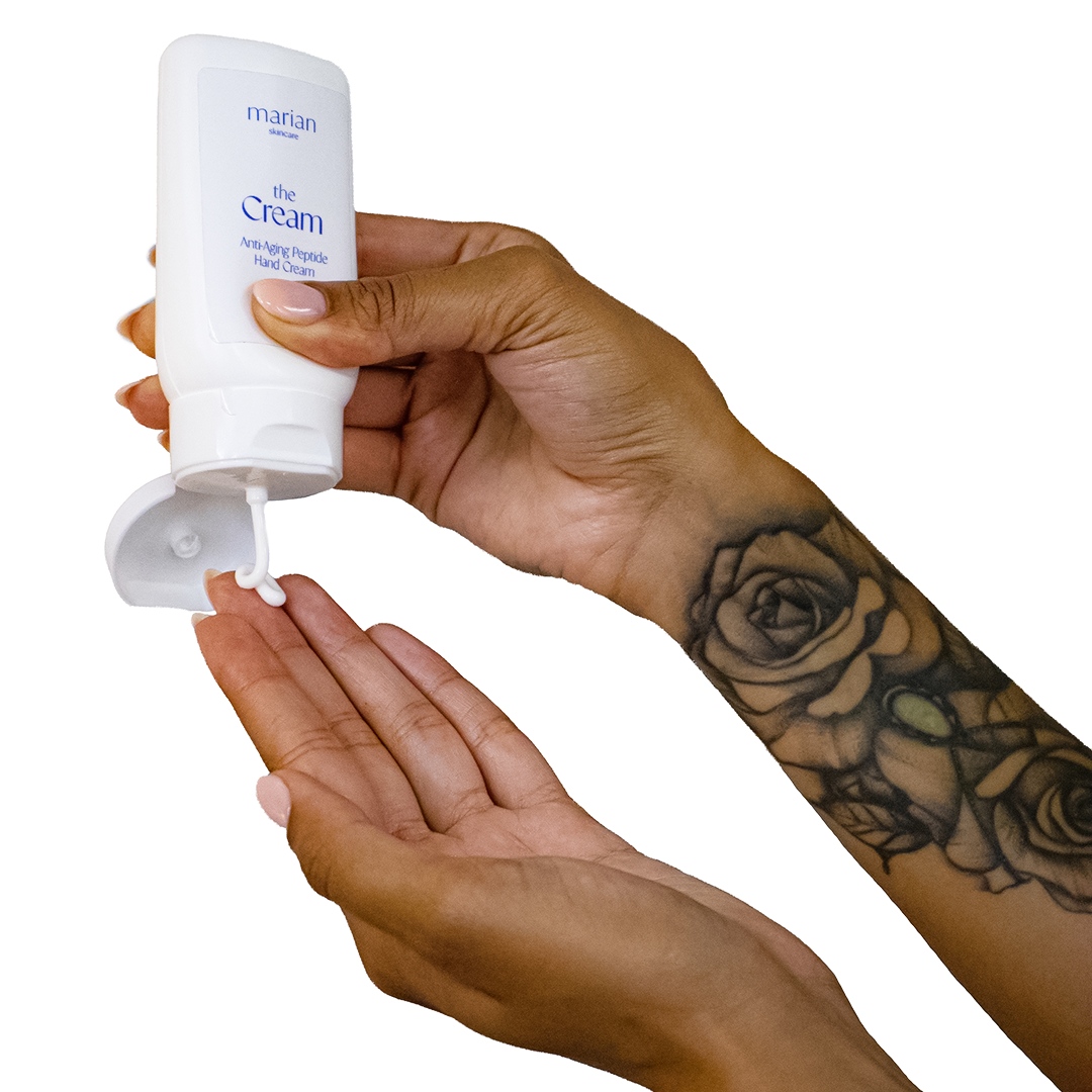 A model holds a white bottle of marian skincare the Cream Anti-Aging Peptide Hand Cream in their right hand and gently squeezes a small amount of the product onto the palm of their left hand.