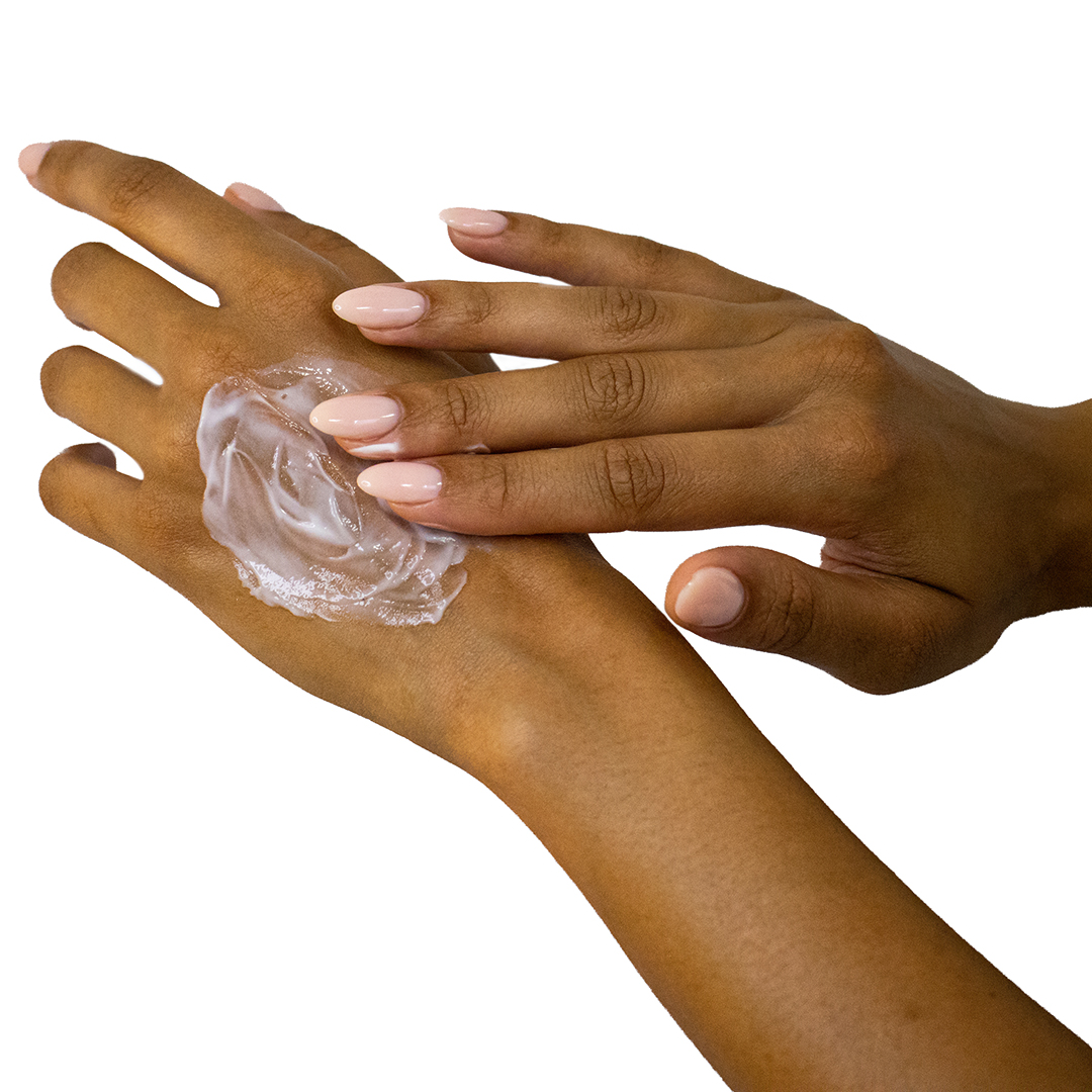 marian skincare the Cream Anti-Aging Peptide Hand Cream; a model rubs a small amount of the marian skincare the Cream Anti-Aging Peptide Hand Cream onto the top of their left hand with their right fingertips.